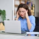 Tired young businesswoman grasping her head, revealing the signs of burnout.