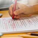 hand holding red pen over proofreading text in office