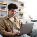 Smiling man using his laptop on the sofa indoors