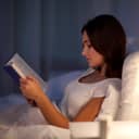 Woman reading a book in bed before sleep