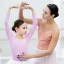 preteen girl performing dance moves under the guidance of a young female ballet instructor