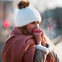 Woman breathing on her hands to keep them warm at cold winter day
