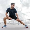 close-up of a young man doing warm-up exercises on a dock, wearing sporty clothes and a smartwatch
