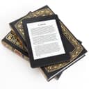 E-reader placed on top of two paper books against white background