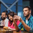 A man using his phone while at a dinner party with his friends