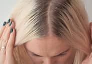 Woman parting her hair to reveal her natural and dyed hair