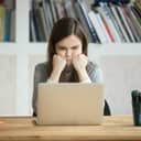 young female office worker staring at a laptop with a frown, disappointed by something she's reading