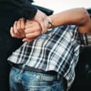 Policeman handcuffing a car thief during an arrest on the road