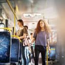 A young woman walking down the aisle in a bus