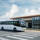 A white passenger bus parking near an airport.