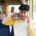 A young man trying to talk on the phone in a public transport