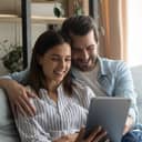 A couple using at a tablet while sitting on a couch 