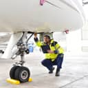 A man crouching under an airplane nose making final checks