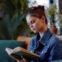 young woman sitting on a couch and reading a book in a cozy living room