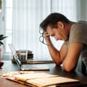 A stressed man looking at his laptop