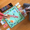 Two people playing Monopoly and showing all the money they have to each other while sitting on the floor