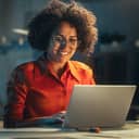 Happy-looking woman working at her laptop in the evening.