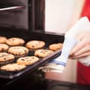 close-up of freshly baked chocolate chip cookies on a pan, woman taking them out of the oven