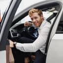 Man smiling out of the driver's seat of his car