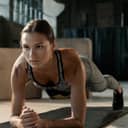 A girl in fitness attire doing a plank on the yoga mat