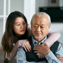granddaughter comforting her sad elderly grandfather seated on the living room couch at home