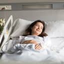 A young smiling woman laying in a hospital bed