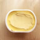 Top, close-up view of a container of margarine on a wooden surface.