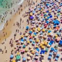 aerial shot of a crowded Rio de Janeiro's Copacabana Beach with colorful umbrellas and ocean swimmers on a hot summer day