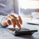 Accountant using a calculator to work on a financial report at his office desk