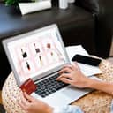 Close-up of a young woman shopping online, ordering cosmetic products on her laptop.