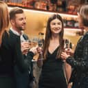 A group of stylishly dressed individuals celebrating a special occasion in a restaurant setting and drinking champagne.