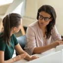 two businesswomen talking with each other in a modern office setup