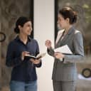 Two businesswomen talking with each other in the office hallway
