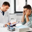 A doctor reading results to a patient holding hands on his head