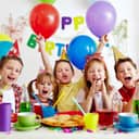 Kids celebrating at a birthday party with balloons and colorful cups.