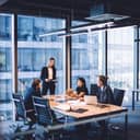 team of four in formal attire brainstorming over business ideas at a table in a contemporary office setting