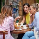 group of girlfriends talking about different topics while drinking coffee in a cafe