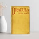 Bram Stocker's "Dracula" on a white table next to a white vase with dry flowers