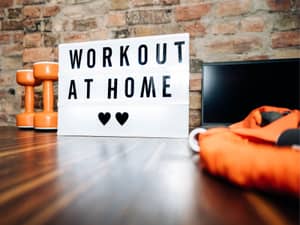 A board with Workout at Home written on it next to weights and a bag