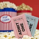Two cinema tickets in front of buckets of popcorn