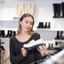 young woman checking out a pair of white moccasins from a new footwear collection in a shop