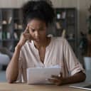 A confused young woman reading a paper document, concerned about the results of research.