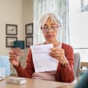 A senior woman holding medicine and reading about side effects