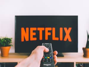 A person pointing a remote at a TV with a Netflix logo on