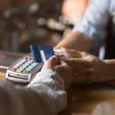 A person paying by card at a POS system in the store.