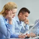 Two worried workers sitting at an office desk reviewing documentation