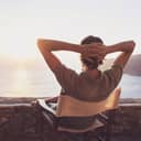 Man at the seaside sitting in chair enjoying the view of sunset