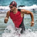 close-up of a determined male triathlete in professional gear sprinting out of the water during Ironman race