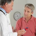 A doctor holding a model of a heart talking to a patient