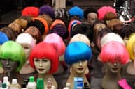 A lot of different colored wigs on mannequin heads